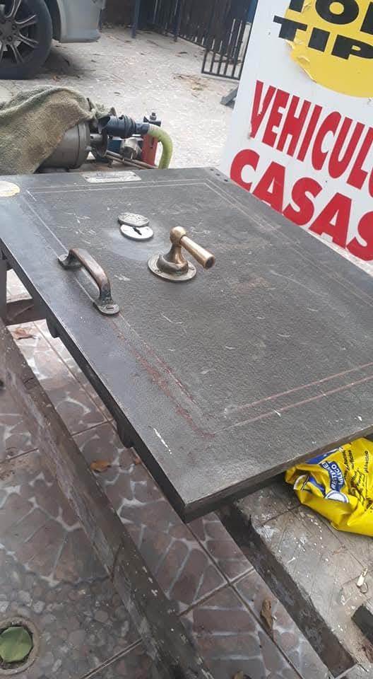 Puerta de caja fuerte antigua desmontada, con mecanismo y manilla de bronce a la vista