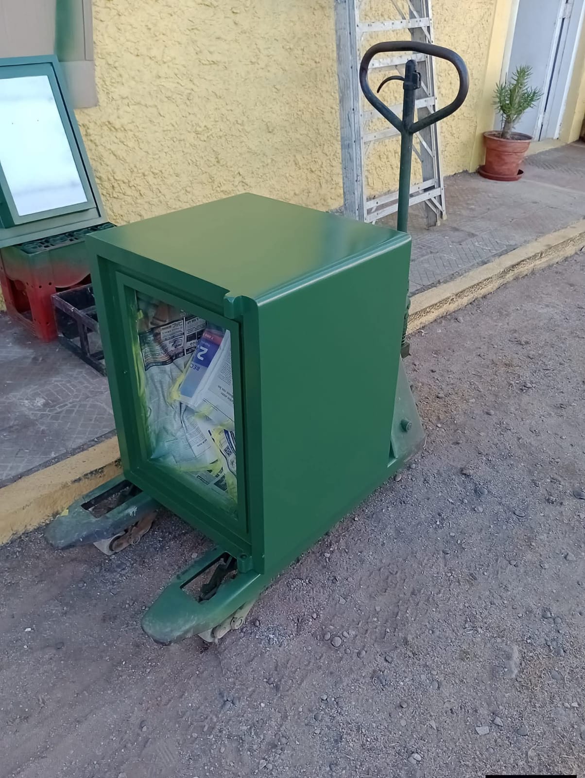 Caja fuerte verde sobre carro hidráulico, lista para traslado