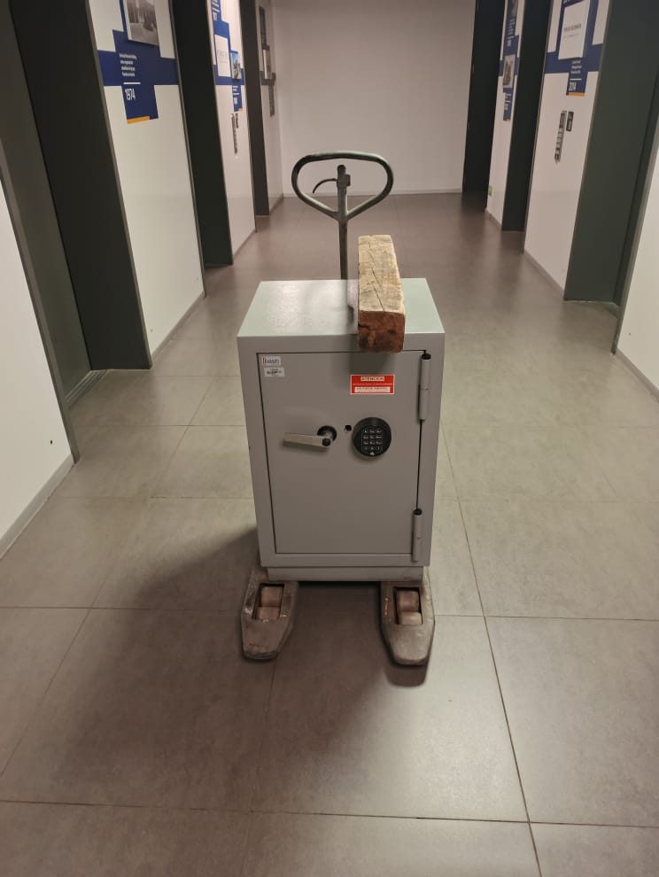 Caja fuerte gris con cerradura electrónica sobre transpaleta en un pasillo de oficinas