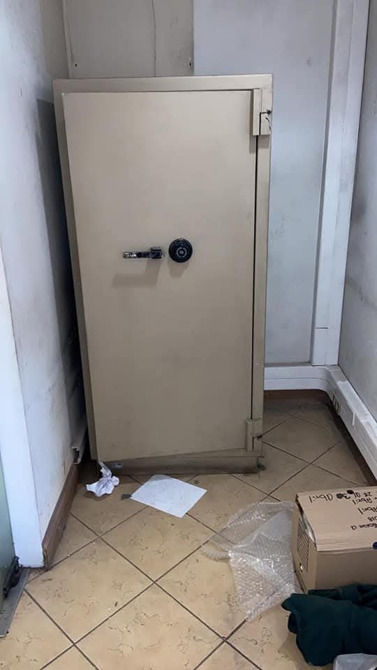Caja fuerte color beige en rincón de bodega, lista para su traslado